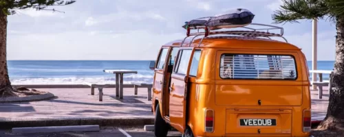 Orange Volkswagen Camper parked along the seafront